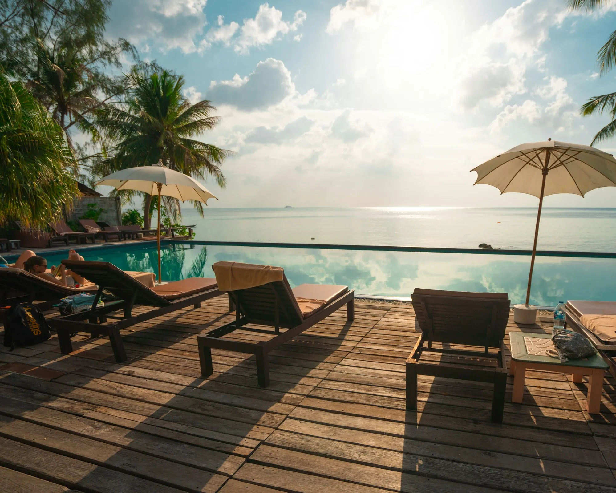 Loungers and umbrellas beside an infinity pool looking out to the sea