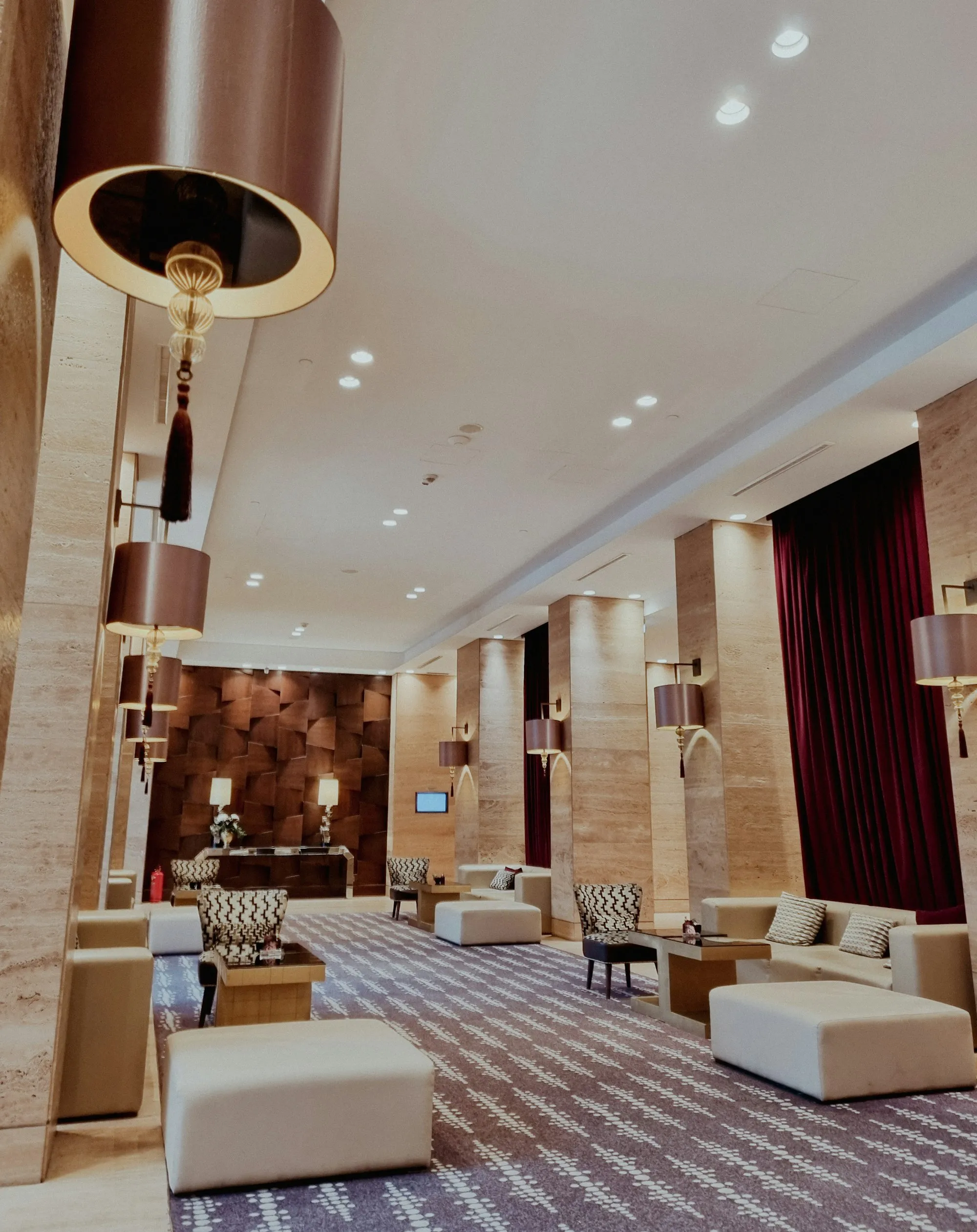 A hotel lobby with soft lighting, seating and a chandelier