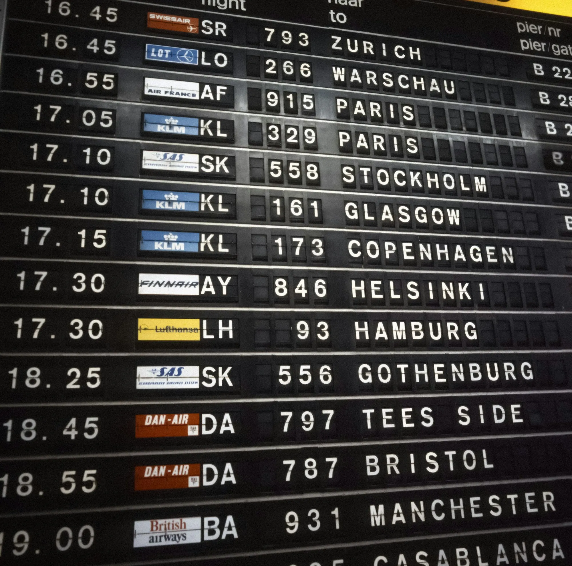 A classic split-flap airport departure board listing European destinations and flight numbers