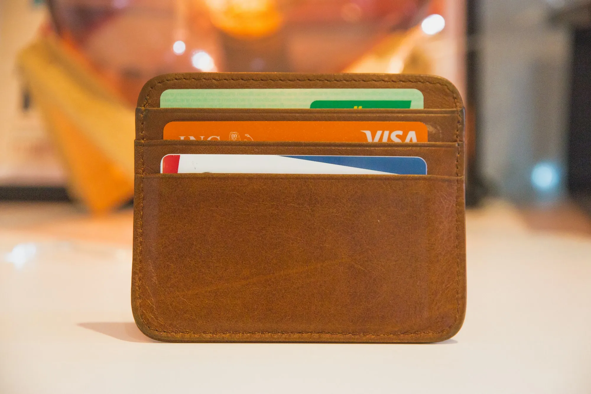 A leather card holder on a table with several credit cards tucked inside