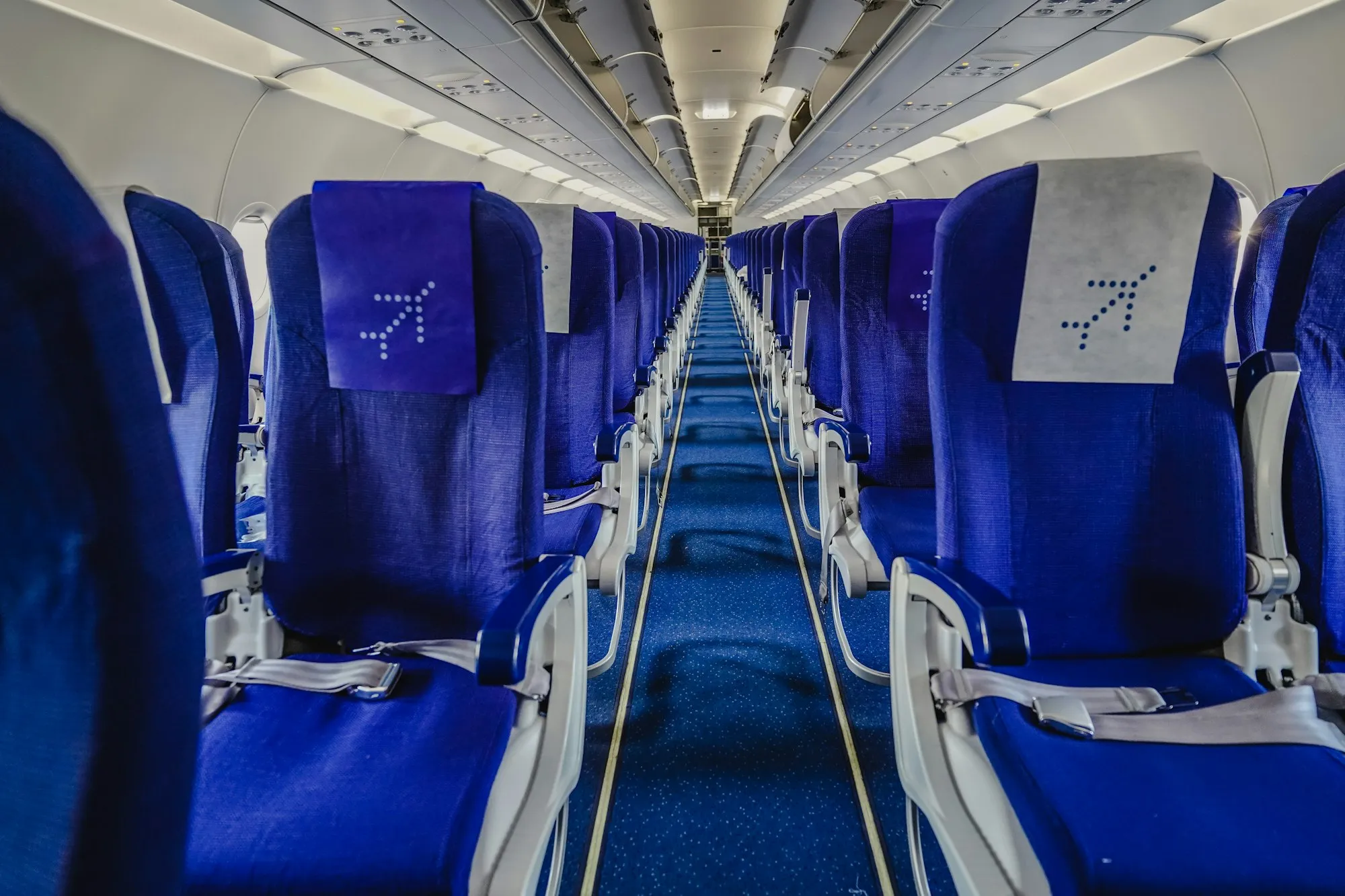 Looking down the aisle of a narrowbody aircraft cabin lined with blue seats