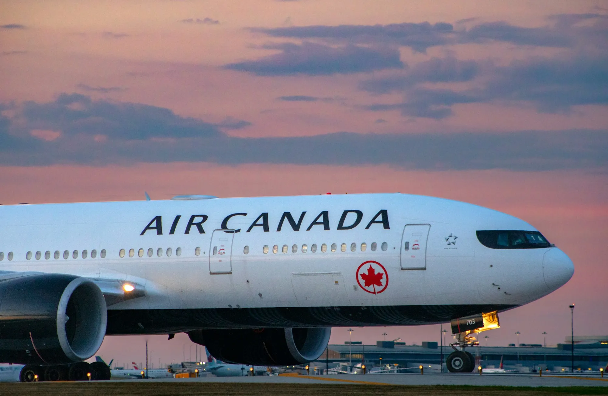 An Air Canada Boeing 777 taxiing at dusk under a pink sky