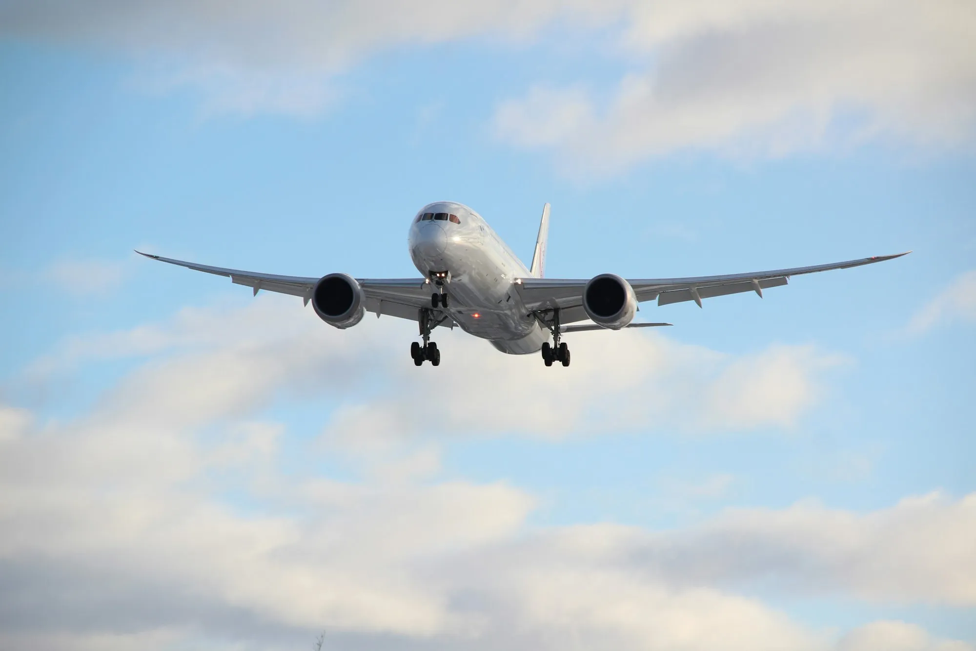 A passenger jet in flight against a pale daytime sky