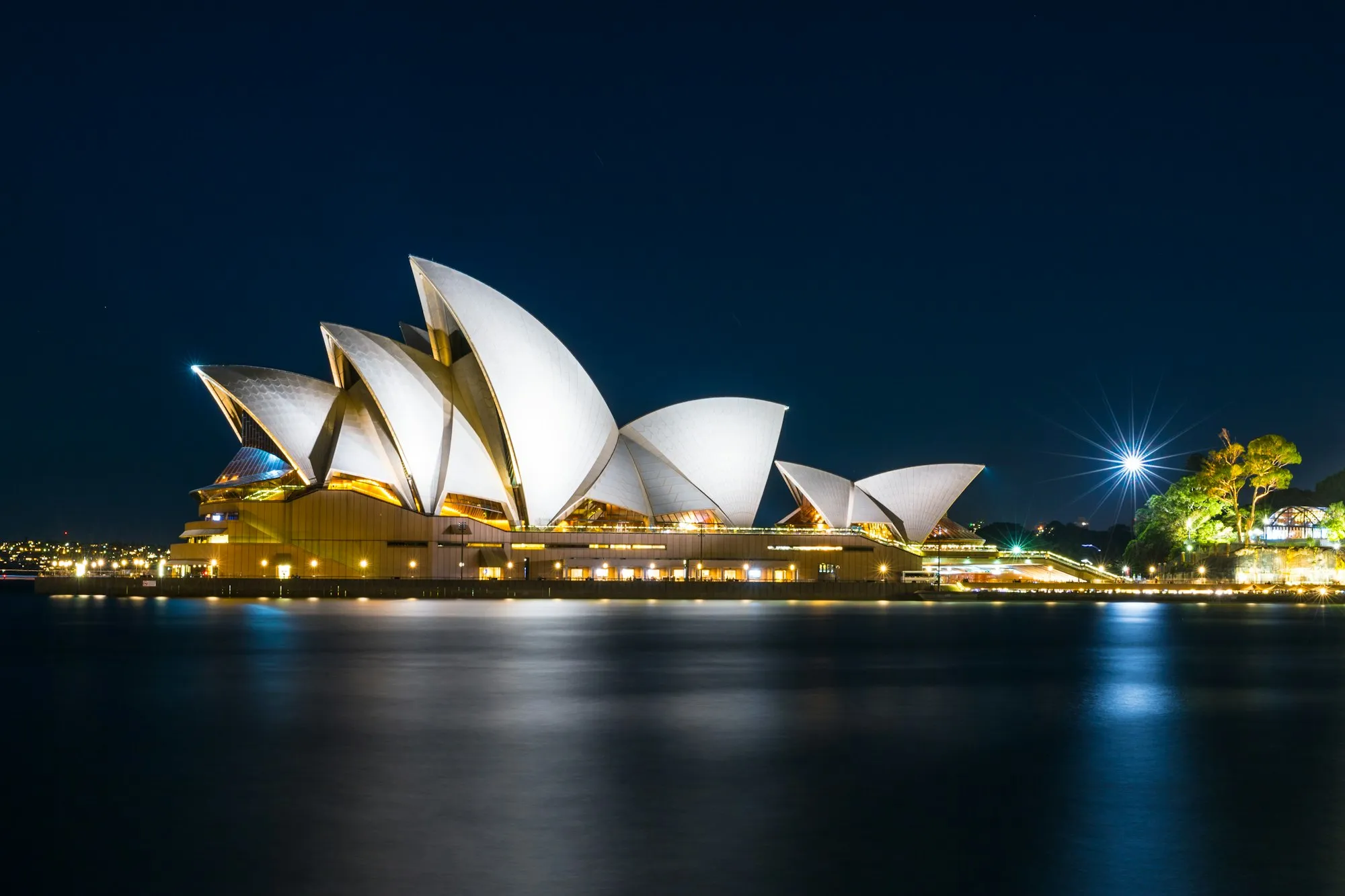 The Sydney Opera House lit up at night across the harbour