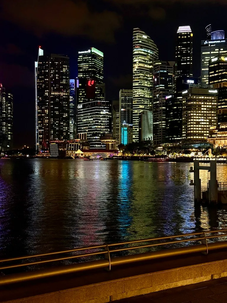 The Singapore skyline at night, office towers reflected in the water of Marina Bay